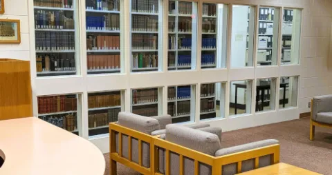 view of seating area in the Archives reading room with windows on left looking into the vault